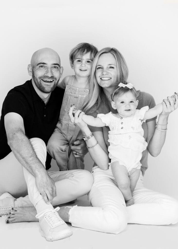 Smiling family of four in cozy, joyful pose, perfect for natural and timeless family photos at home.