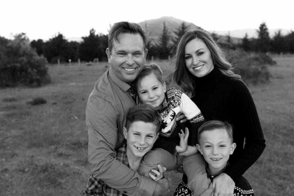 Smiling family of five posing together in an outdoor field during a professional family photography session in San Luis Obispo.