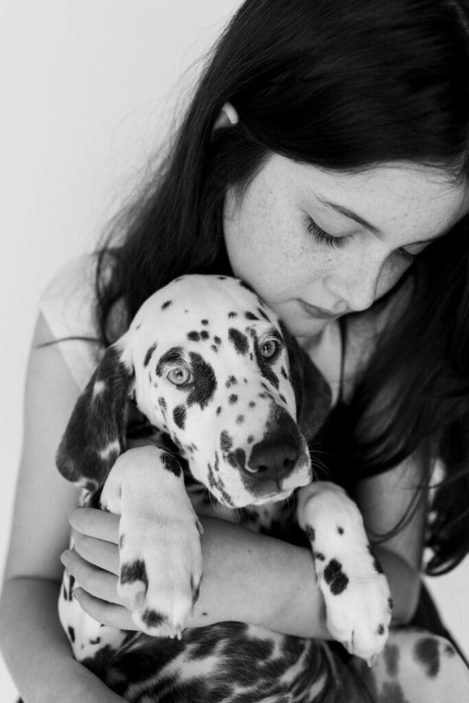 Girl gently hugging Dalmatian puppy 