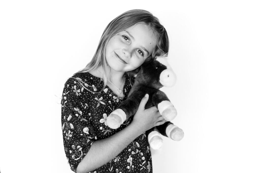 Young girl smiling and holding stuffed animal horse