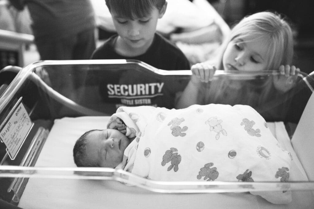 Older siblings admire their new baby brother in the hospital bassinet during Fresh 48 photos.