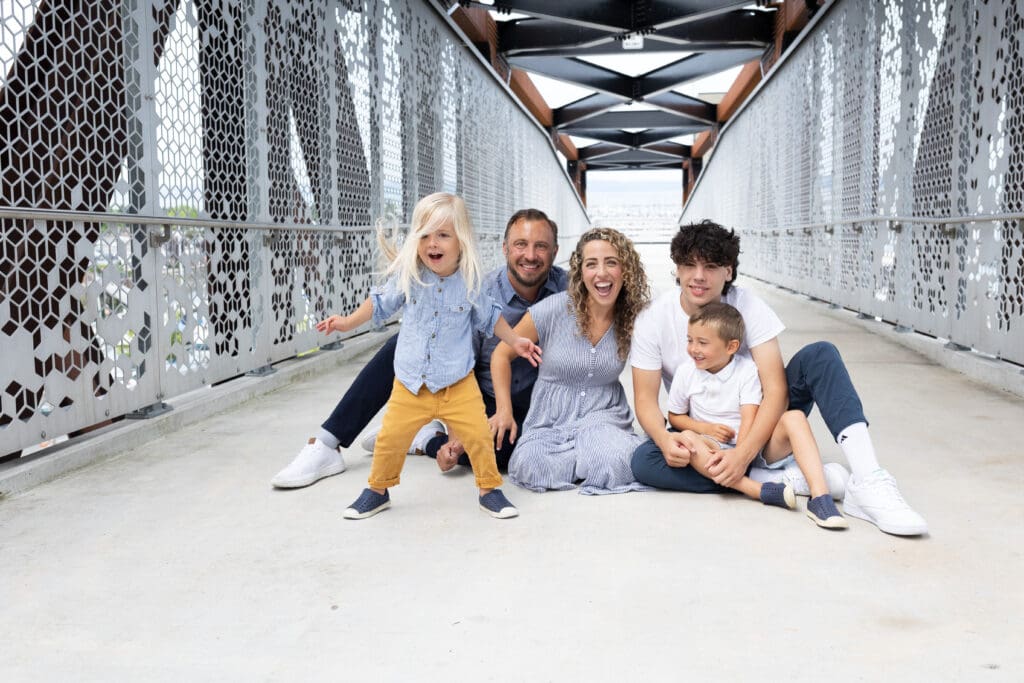 Smiling family sitting on a modern bridge, perfect for questions to ask a photographer before you book.