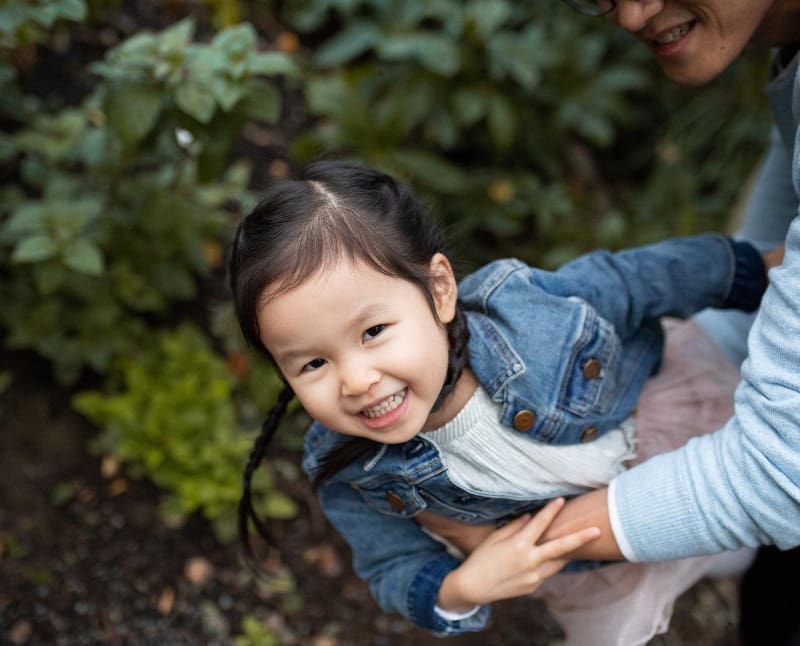 Young girl smiling mid-swing in a playful moment, capturing joyful moments in motion.