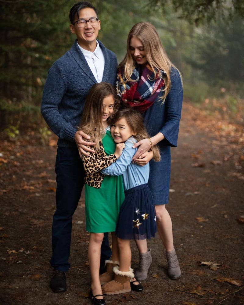 Family cuddled close on a forest path, sharing moments on a foggy autumn day.