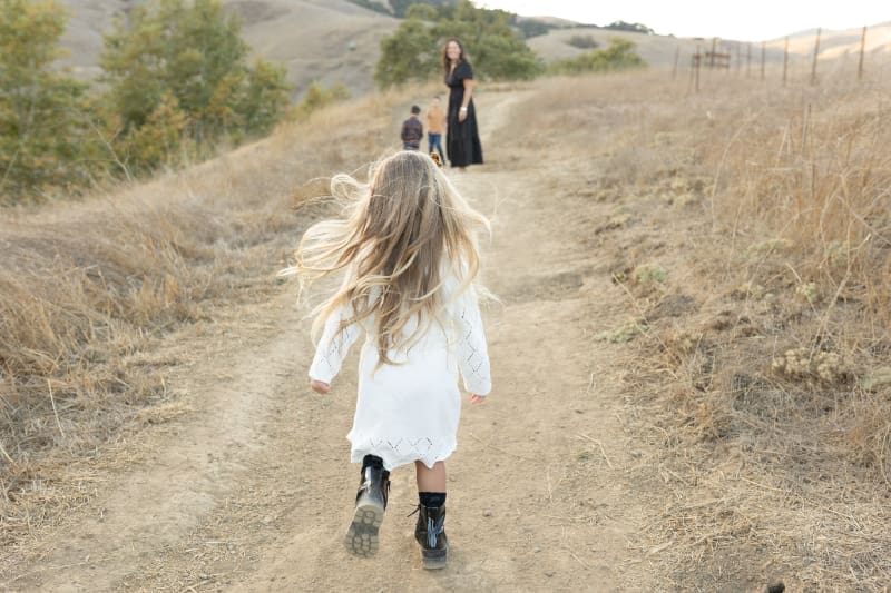 Young girl running up a dusty trail toward her family
