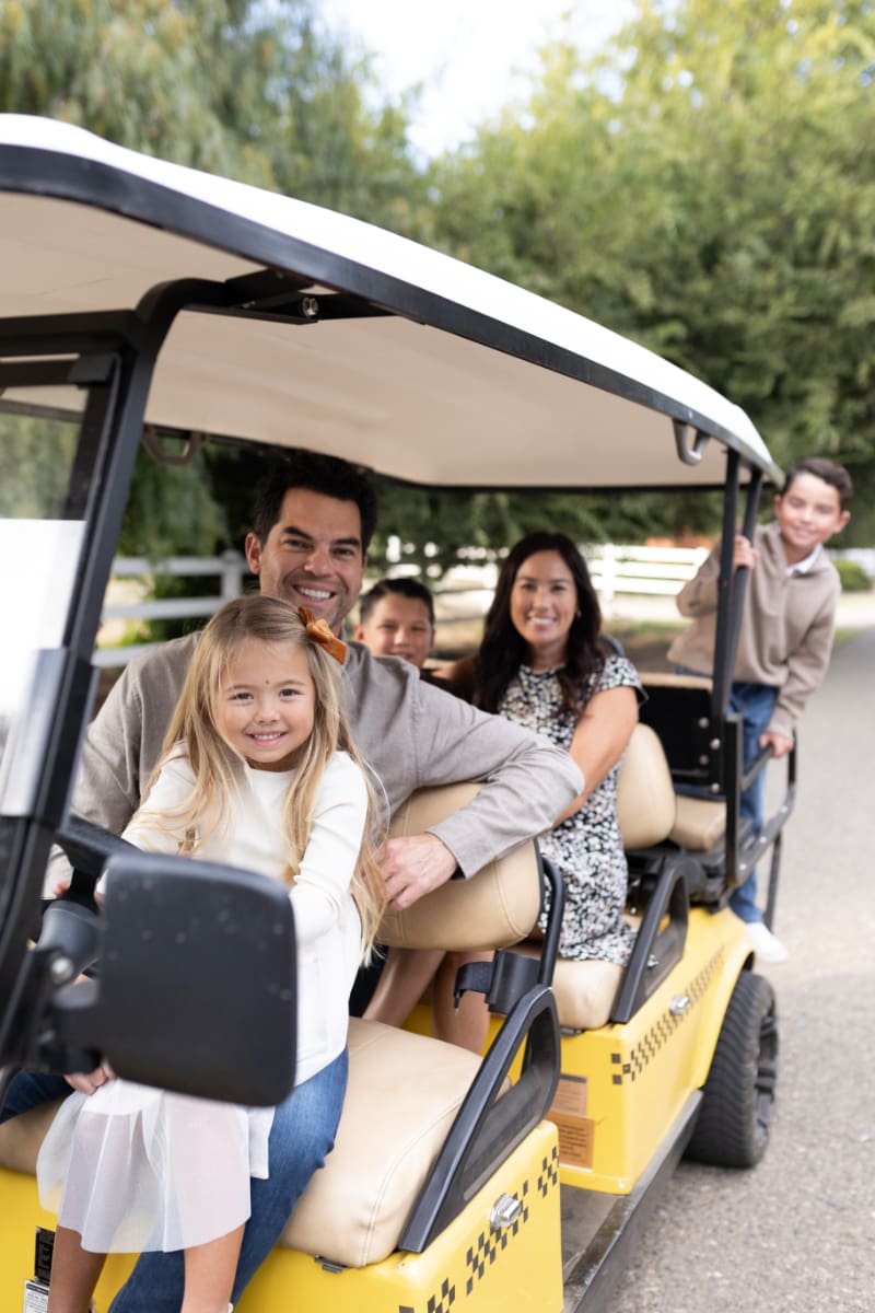 Smiling family on golf cart during outdoor session, showing how to feel confident in front of the camera.