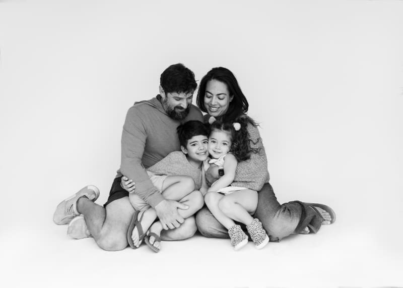 Family sitting close together in studio, sharing a quiet moment that reflects deep family bonding.