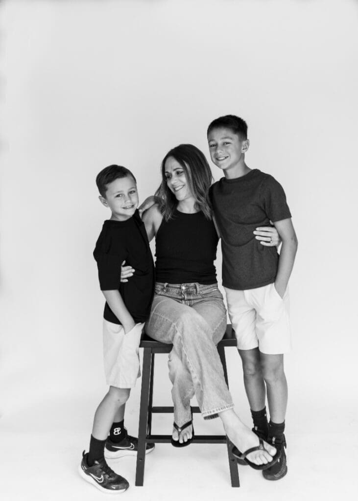 Mother sitting with her two sons in studio, sharing smiles and a moment of genuine family bonding.