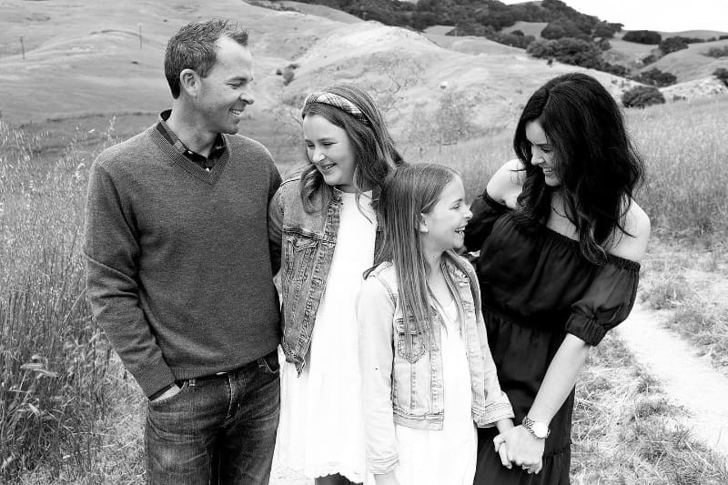 Timeless photography of family laughing together in open hills during outdoor session.