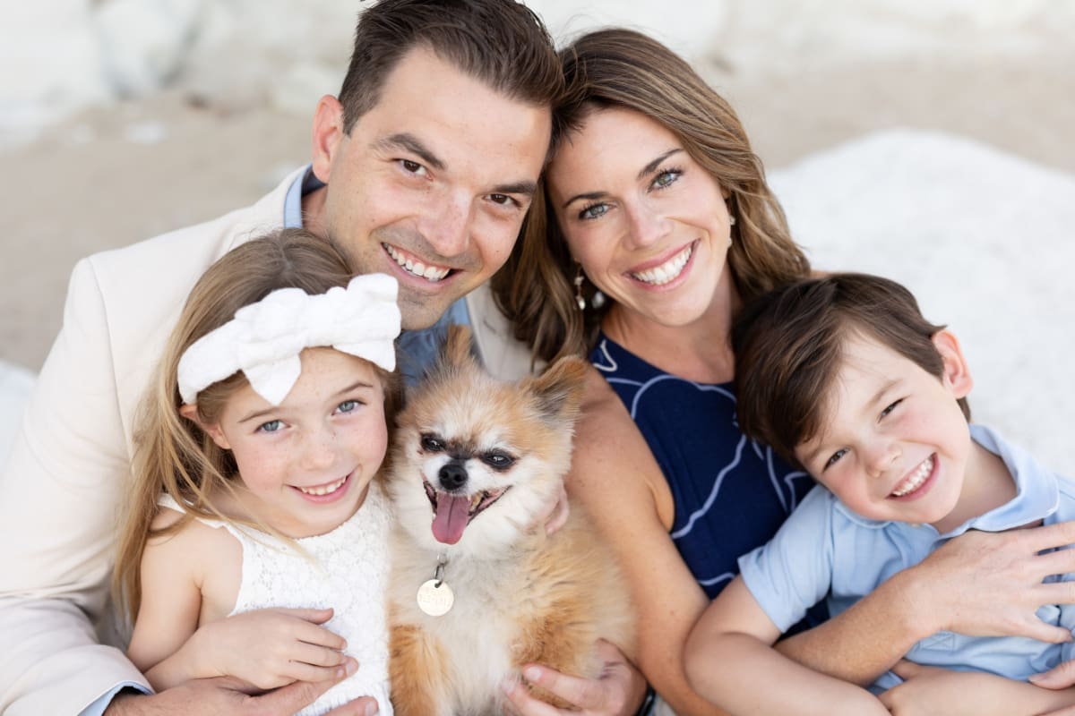 Photos of smiling parents, two kids, and small dog cuddled together on sandy shore