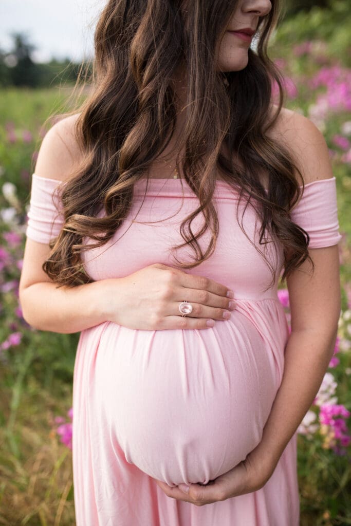 Pregnant mother in pink dress holding baby bump, inspiring maternity photo ideas for outdoor sessions.
