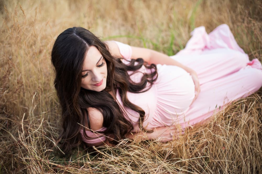 Pregnant mother relaxing in a grassy field, showcasing natural and timeless maternity photo ideas.